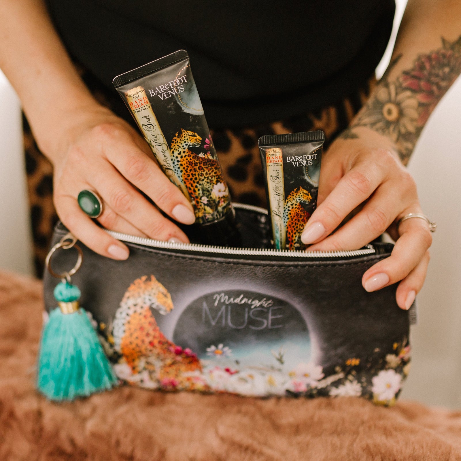 Person removing two Barefoot Venus products from a pouch with text 'Midnight Muse', a leopard and floral design.