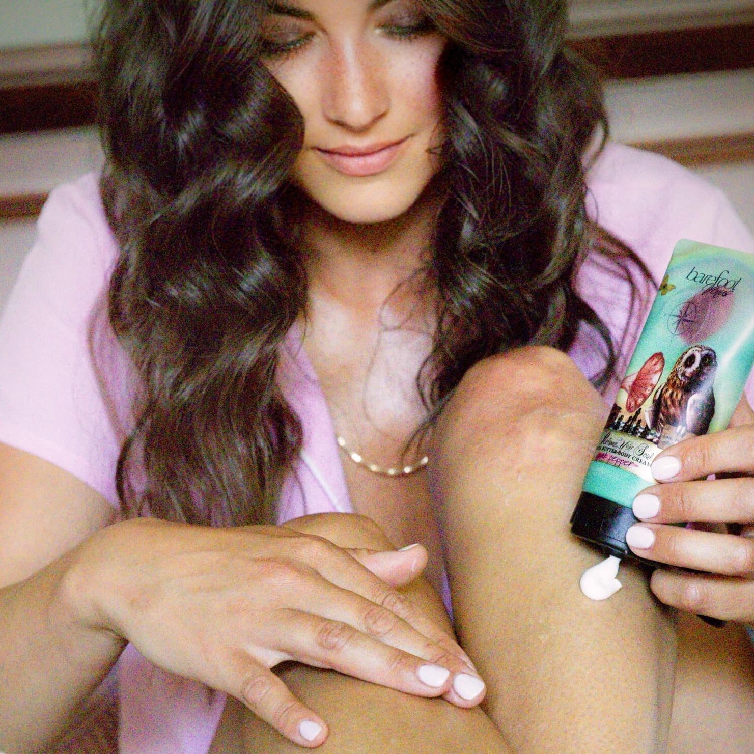 A person is applying pink pepper body cream to their skin.