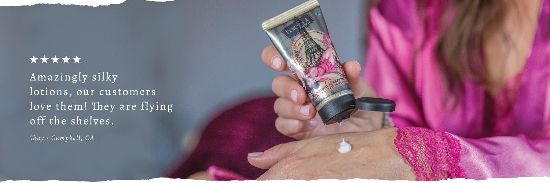 Person in pink robe applying Ruby Red hand cream. Text overlay reads 'Amazingly silky lotions, our customers love them! They are flying off the shelves. - Thuy - Campbell, CA'.