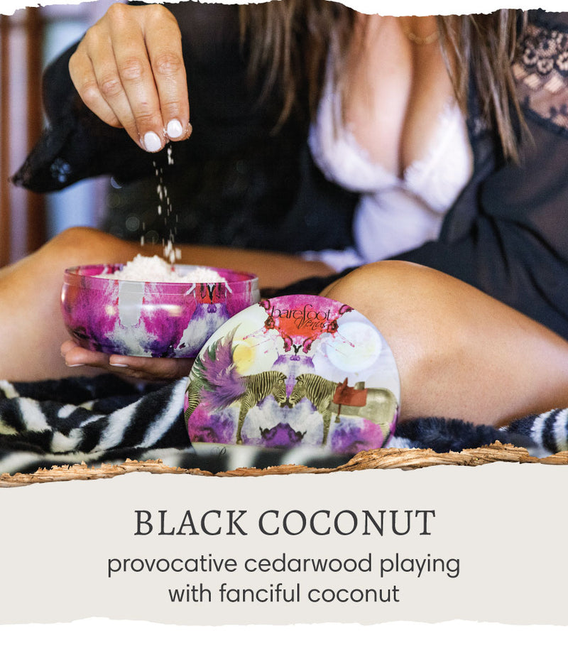 Person sprinkling Barefoot Venus Black Coconut Himalayan pink salts into product container with text 'Black Coconut - a provocative cedar wood playing with fanciful coconut'.