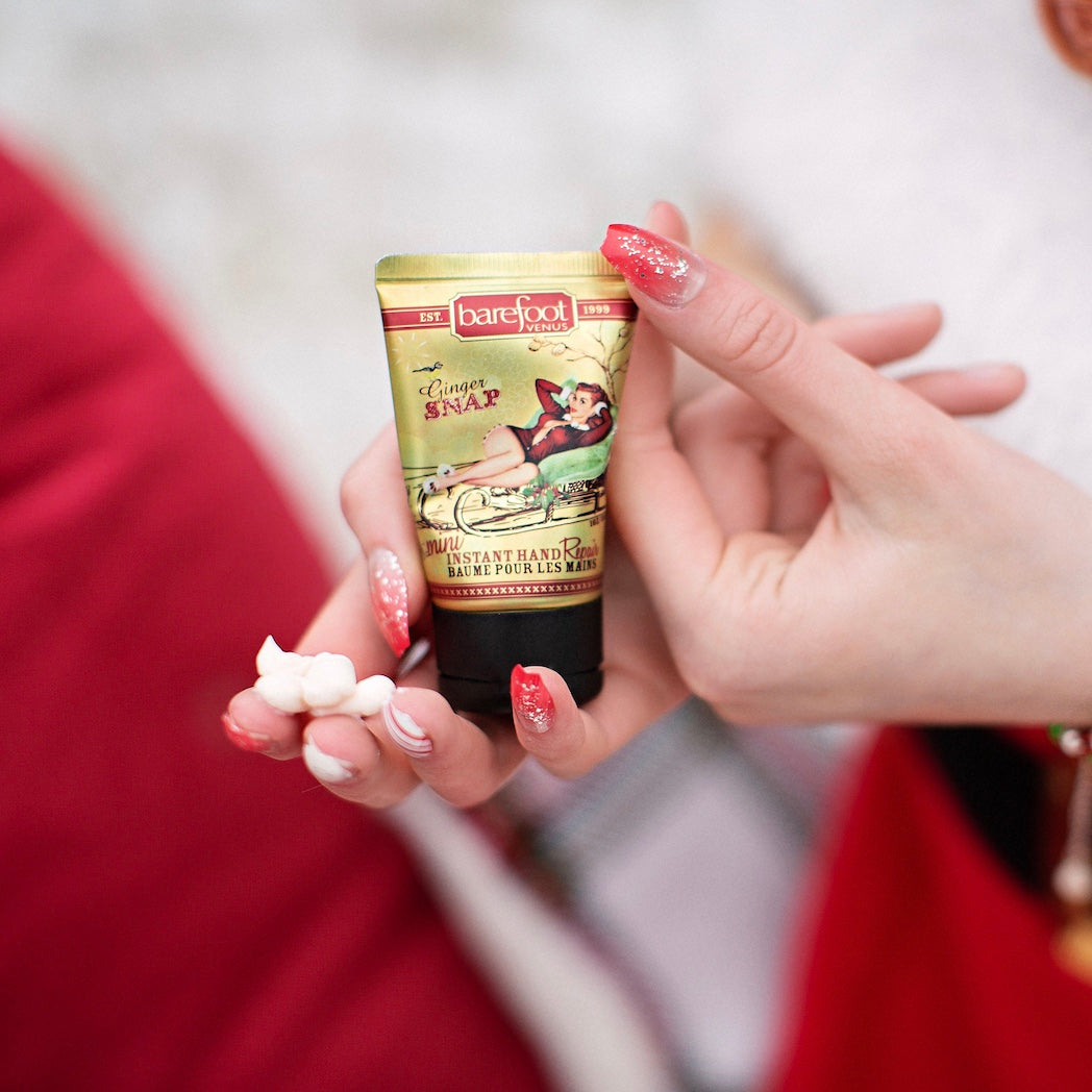 A tube of 'Ginger Snap' mini hand repair cream held between fingers, with a decorative label featuring a woman on a sled and text.