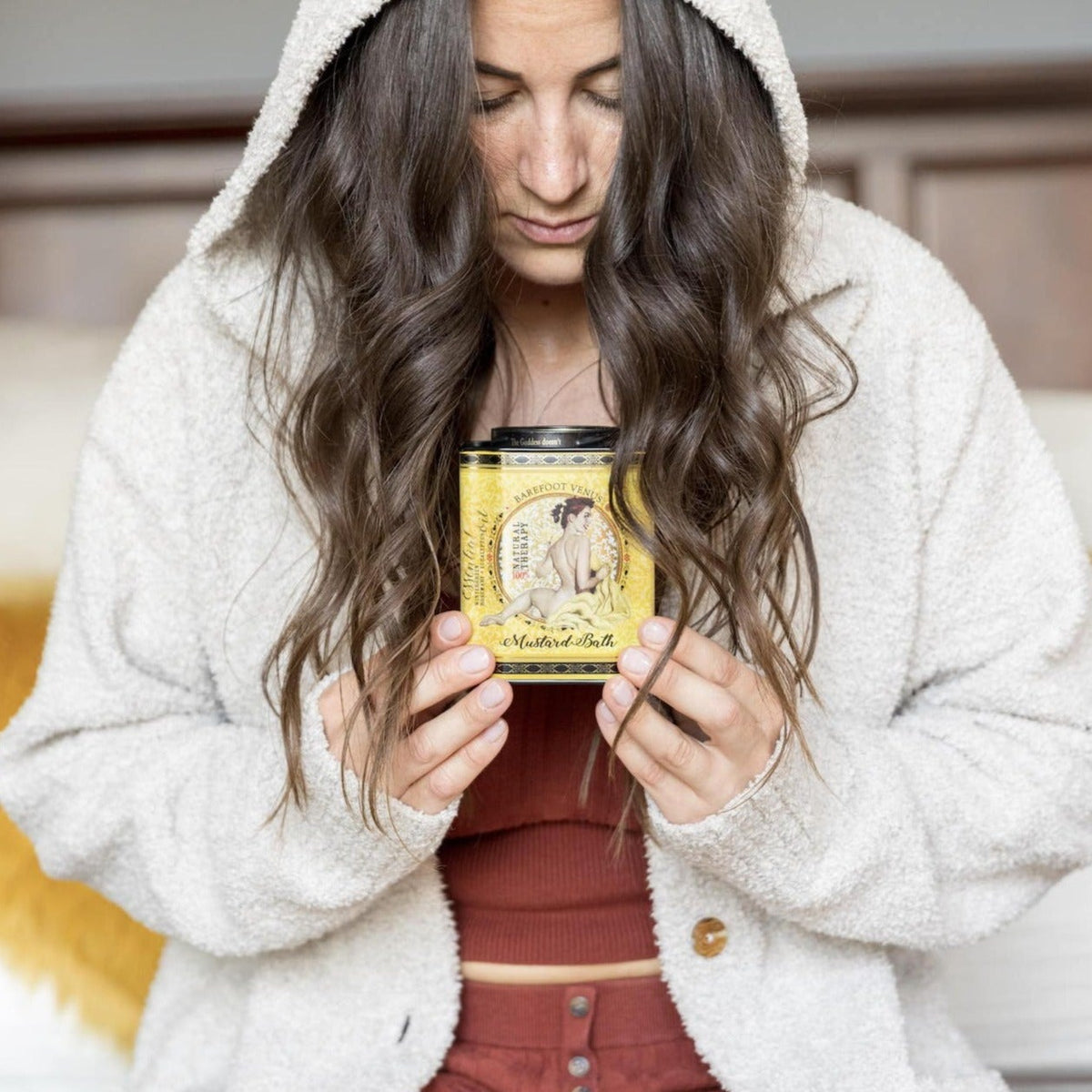 Person holding a Barefoot Venus mustard bath, bath soak tin with long hair.