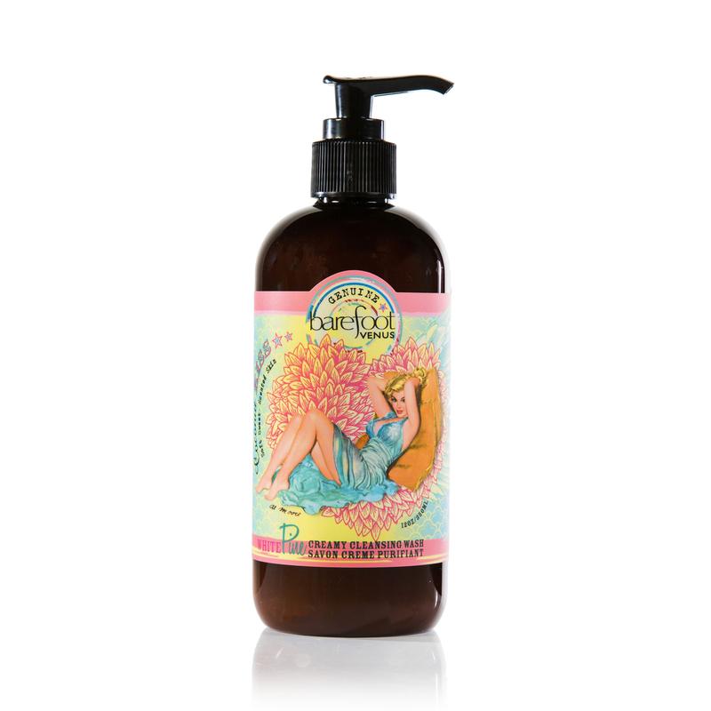 A dark brown bottle with a pump dispenser of Barefoot Venus Coconut Kiss creamy cleansing wash featuring a woman in a blue dress with a floral background design on a white background.