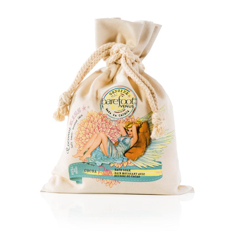 Canvas bag of Barefoot Venus Coconut Kiss bath soak product featuring a woman in a blue dress with a floral background design on a white background.