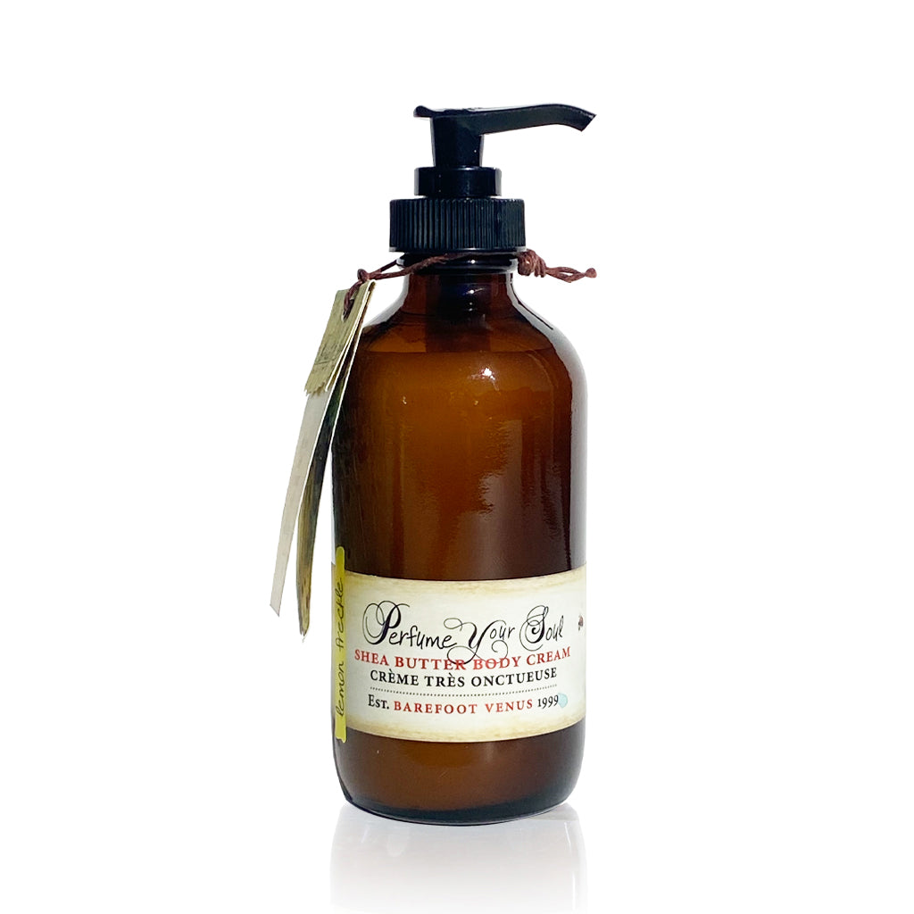 A person holding a bottle of Lemon Freckle body cream with a pump dispenser. The label on the bottle features an illustration of a woman's face with freckles and a floral crown.