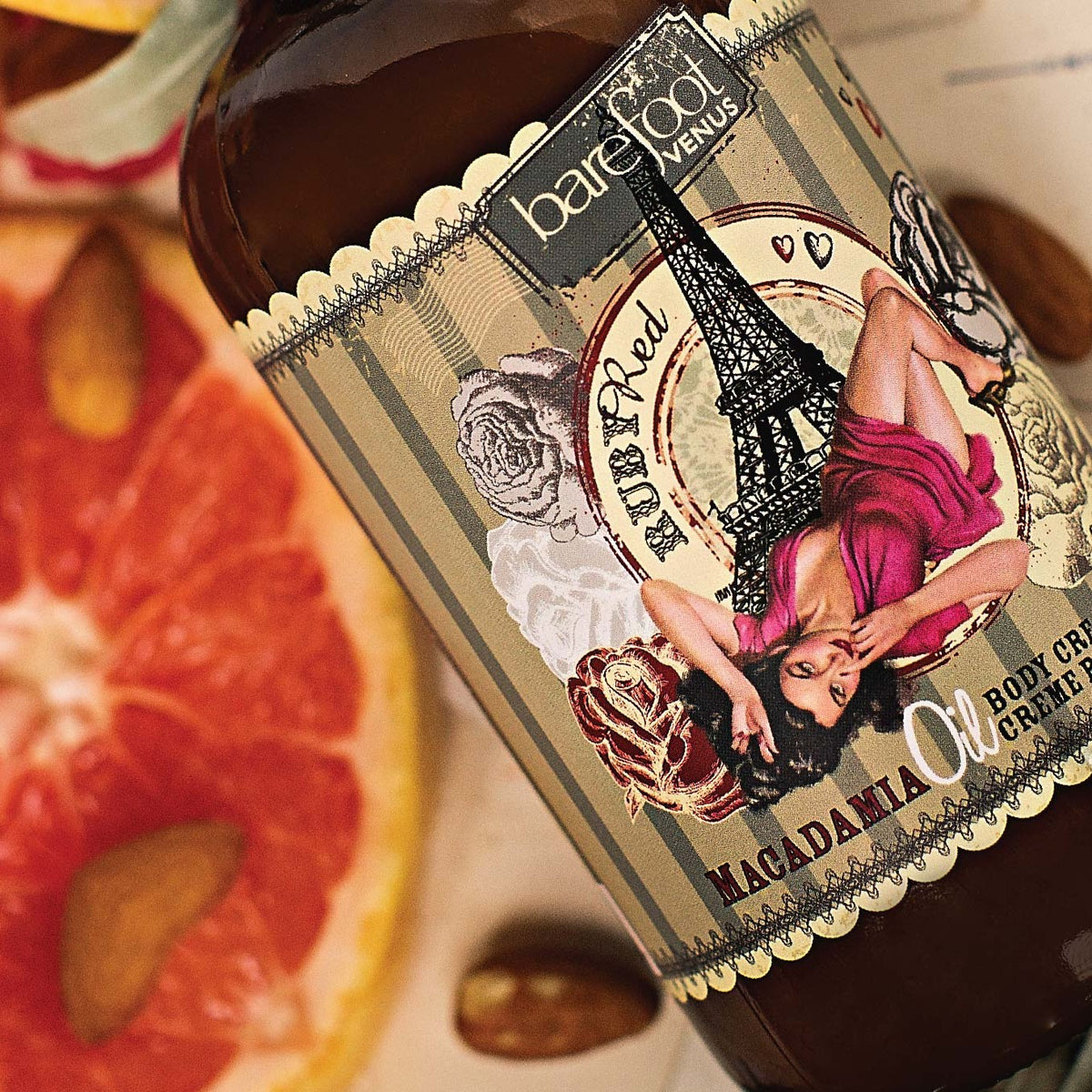 Close up of Barefoot Venus Ruby Red body cream label with grapefruit and nuts in a blurred background.