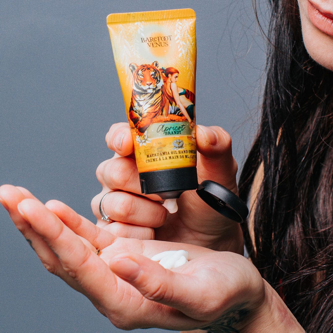 A tube of Apricot Brandy macadamia oil hand cream with a label featuring illustrations of a tiger and woman.