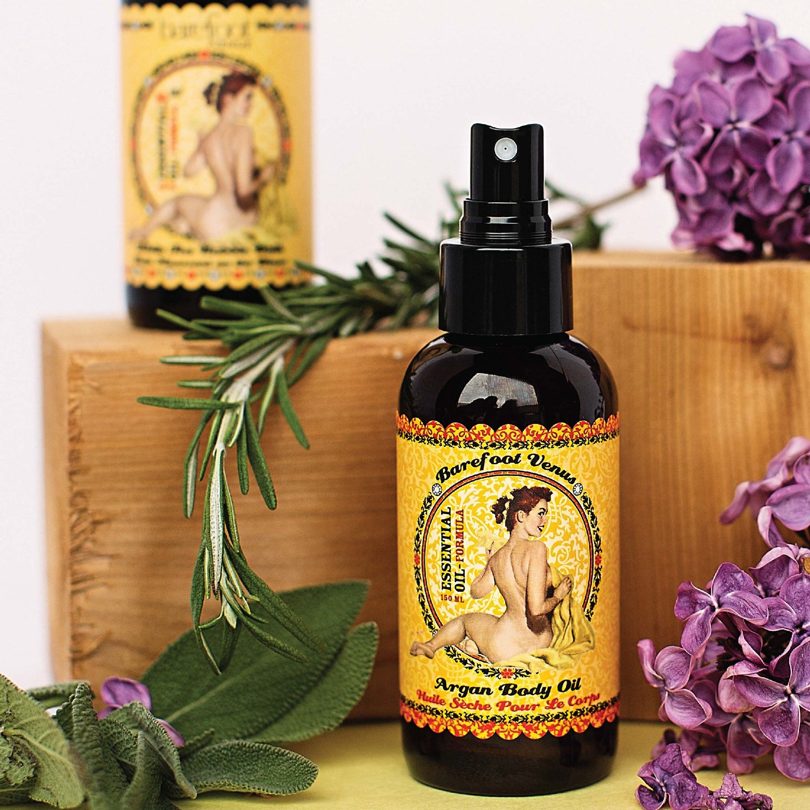 A spray bottle of Barefoot Venus Essential Oil Argan body oil with a vintage woman design on the packaging on a white background.